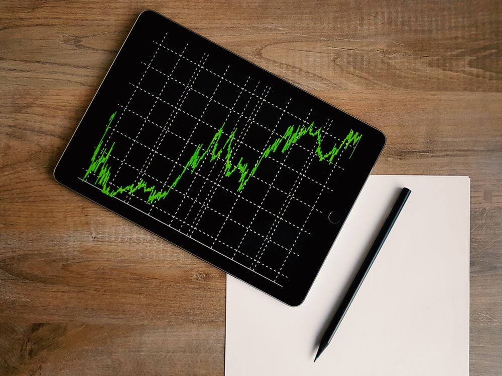 tablet with a green signal graph and a piece of paper with a pen lying on it