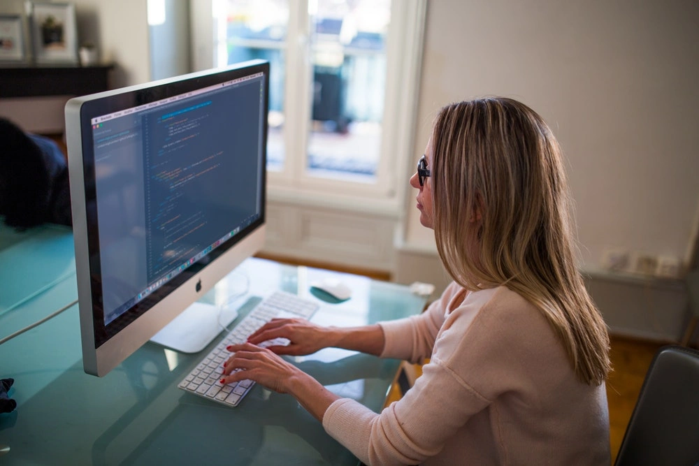woman looking at lines of code on a Mac screen