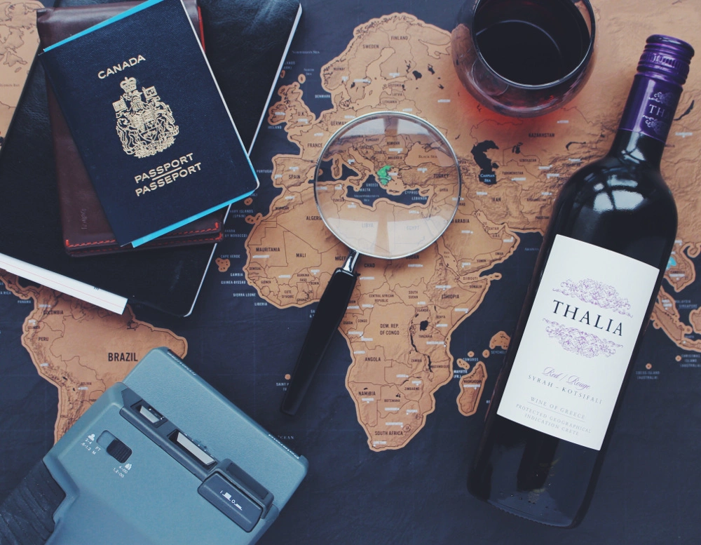 a map with a looking glass, glass of wine, an analogue camera and a passport on it