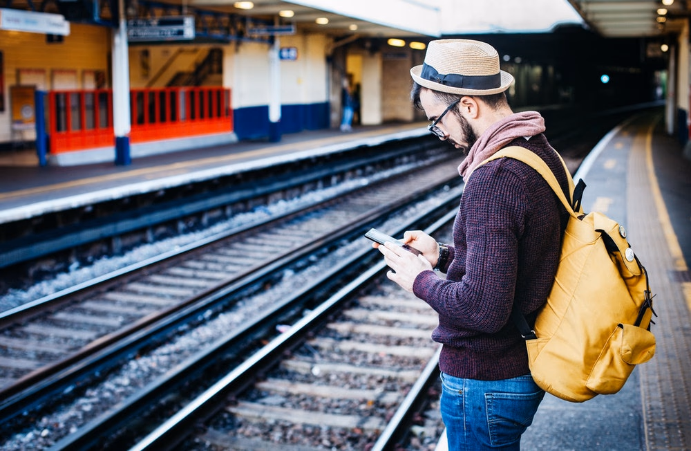 a man using his phone on a train station