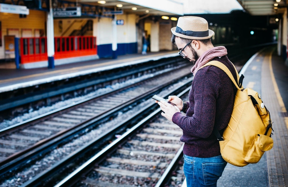 a man using his phone on a train station