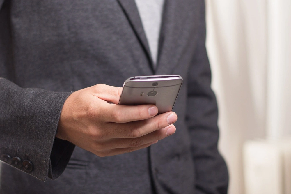 a man in a grey suit jacket looking at his phone