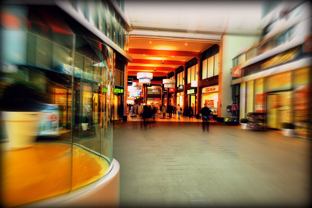 zdjęcie ludzi przechodzących alejką w centrum handlowym